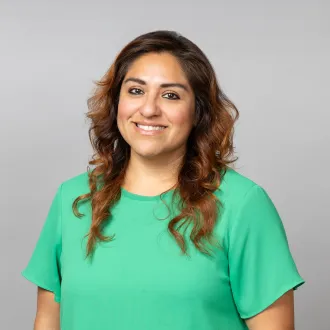 Un retrato de Tahira Rivera, sonriendo y luciendo una blusa de color verde brillante.