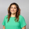 A headshot of Tahira Rivera, smiling and wearing a bright green blouse.