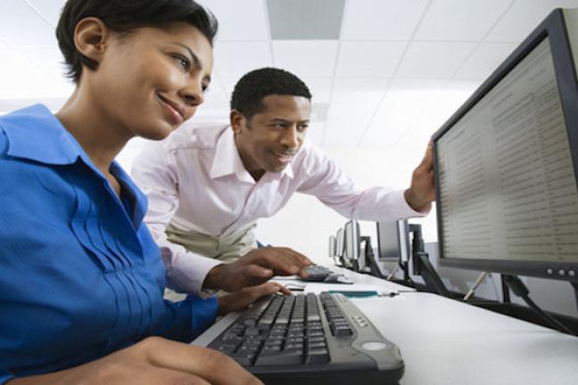 photo of woman at computer with man