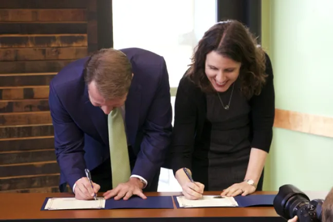 Mayor Bemis (left) and Chair Kafoury sign certificates of their agreement to work together to pursue Promise Zone designation for the Rockwood Community.
