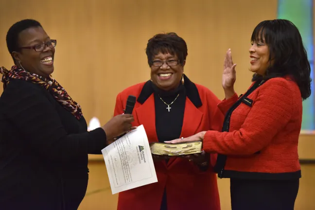 La jueza Adrienne Nelson (izquierda) toma juramento a la comisionada Loretta Smith (derecha) mientras la tía de Smith, Doris Smith (centro), sonríe. 