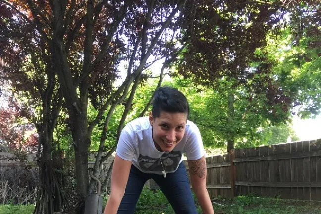 Victim advocate digs hole for fence post.