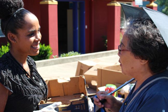 Bienestar staff member Zinnia Zupan chats with an attendee at the Mercado event in July.