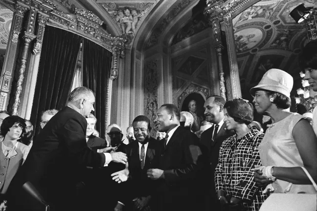 President Lyndon B. Johnson moves to shake hands with Dr. Martin Luther King after the signing of the Voting Rights Act on Aug. 6, 1965