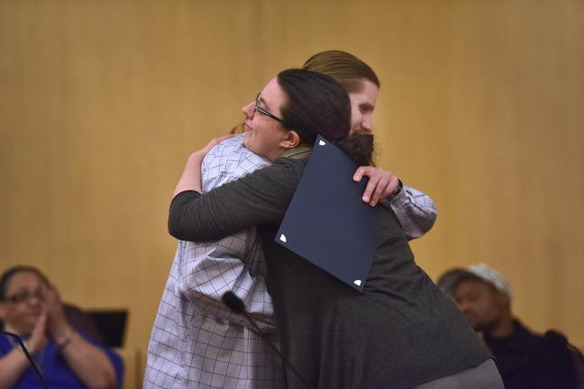 Justice Reinvestment program graduate hugs a service provider during a March graduation ceremony.