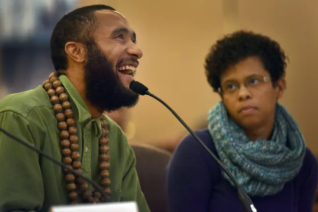 Isaiah Spriggs recites a poem written by a 15-year-old named Shawn at Thursday's board meeting.