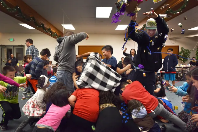 Jessy (right) and Jesus (plaid shirt) oversee the pintata fun at Las Posadas. The teens are in a youth leadership program called STRYVE