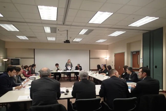 Four delegates from Azerbaijan face away from the camera as they listen to Christina McMahan give an overview of JSD policy and practice