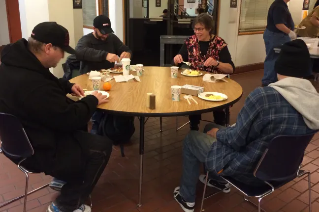 Commissioner Shiprack eating breakfast at a table with three DCJ clients. 