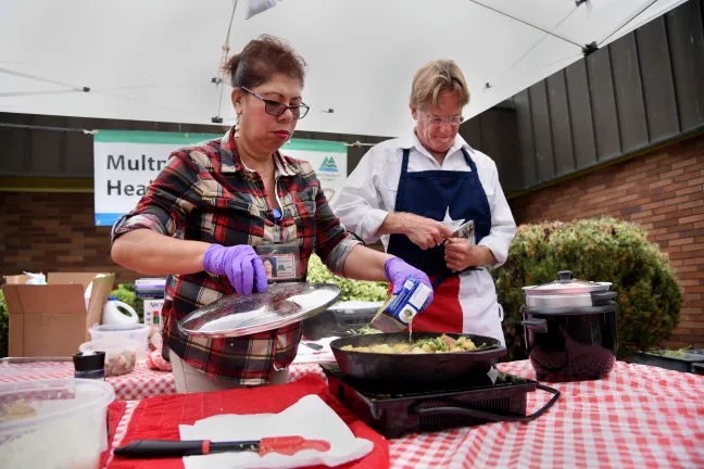 Rockwood Health Center's Jeff Holland and Elisa Sanchez get cooking during a recent demonstration in front of the outer Southeast county clinic.