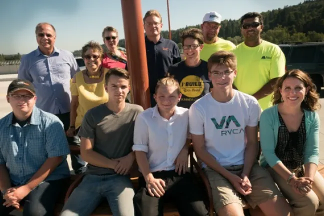 Students, instructors and Sellwood team members gather at bench on bridge.