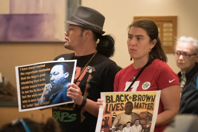 Kate Sherman (left) and Manna Phommathep, stand silently in support as people testify Thursday.
