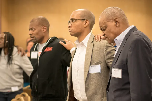 Community members take part in prayer at first Black Men and Boys Healing Summit
