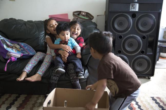 Adelfa's nieces and nephews play with empty boxes as their mothers prepare tamales