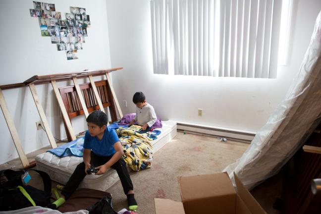 Adelfa's sons, Osmar and Jorge Jr., play video games as she packs up their apartment in the Normandy complex.