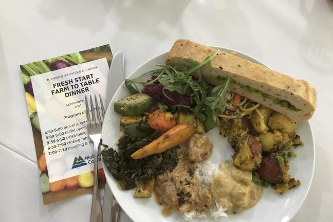 A brochure and a plate of food on a white table