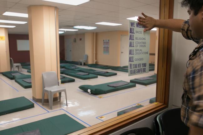 Paul Susi, manager of the 5th Avenue Shelter, hangs a poster a few hours before the first guests arrive Monday, Nov. 20, 2017.