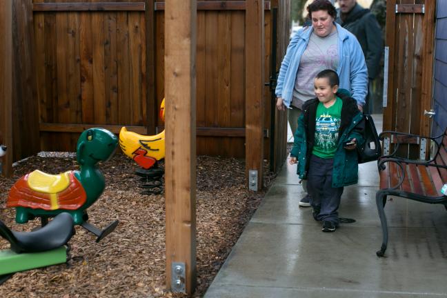 Andrea Bunch watches as her son, Michael, 4, reacts to the playground equipment just outside their new apartment.