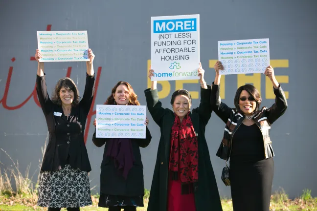 County commissioners hold signs after a housing rally Tuesday, Dec. 5, 2017