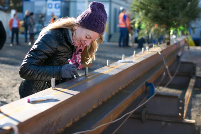 Health Department Co-director Wendy Lear signs the last steel beam.
