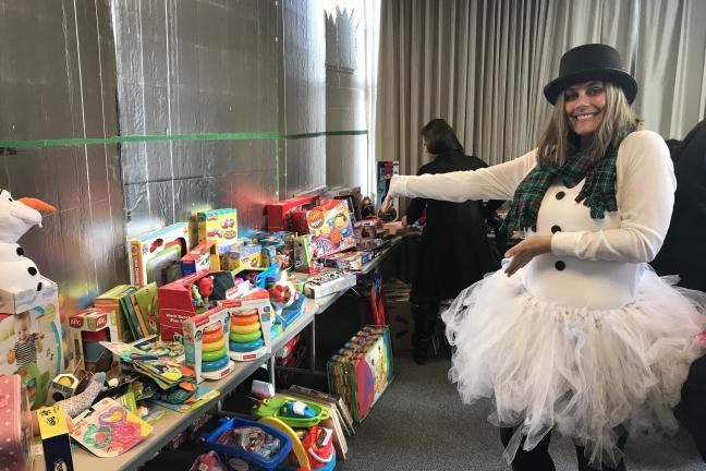 PPO Reed dressed as a snowperson next to a stack of toys