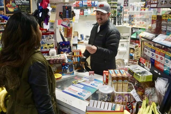 Frederico Villalobos at the Porvenir Mini Mark in East Portland models how vendors should check for ID when people purchase nicotine products.