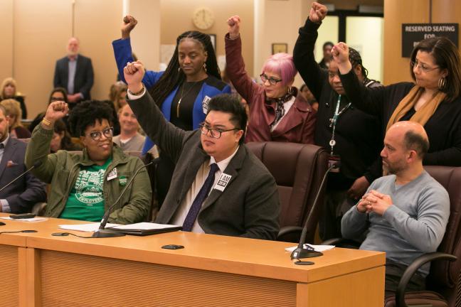 Multnomah County Employees of Color ERG members raise their fists in solidarity at the Thursday’s board meeting. 