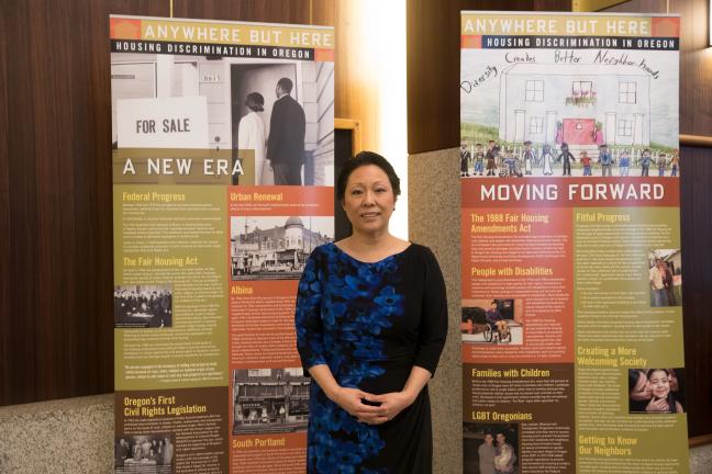 Commissioner Lori Stegmann with an exhibit on housing discrimination on loan from the Fair Housing Council of Oregon.