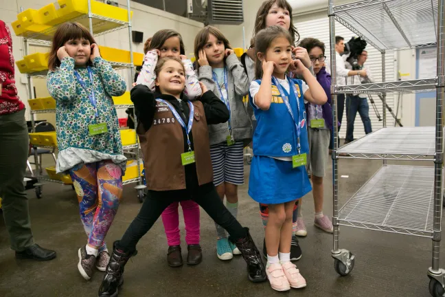 Girl Scouts cover their ears as high-speed sorters, sift and sort ballots. 