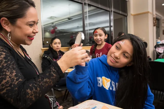 Nurse Christina Licona paints a candy cane on Andrea Garcia Salizar's cheek.