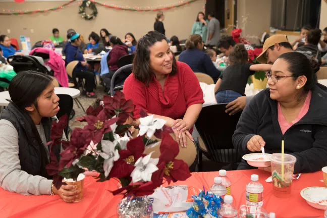 Community health Worker Jessika Fatu chats with clients at the Empezando con Salud holiday party