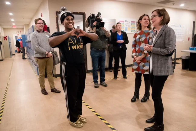 Sean Williams makes a heart with her hands after showing her dance moves to Gov. Kate Brown and Chair Deborah Kafoury at the Gresham Women's Shelter on Dec. 17, 2019.
