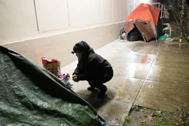 Perlia Bell, an outreach worker with JOIN, talks to a woman about services after handing her gear.