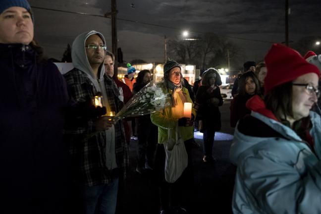 Neighbors and friends hold candles to remember those who have died.