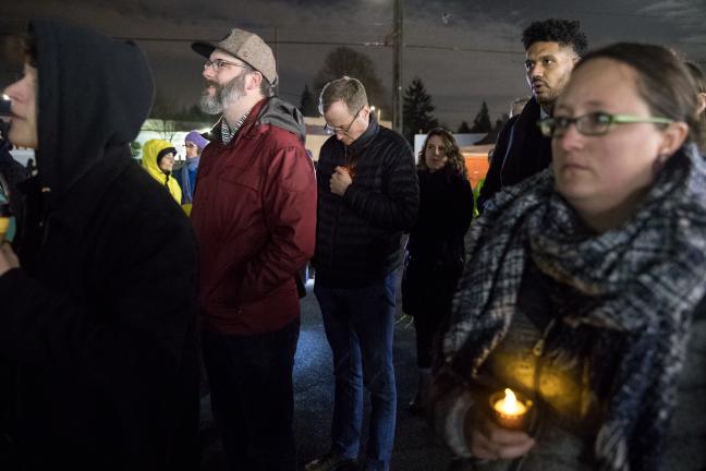 Marc Jolin, center, listens as the names of those who died are read.