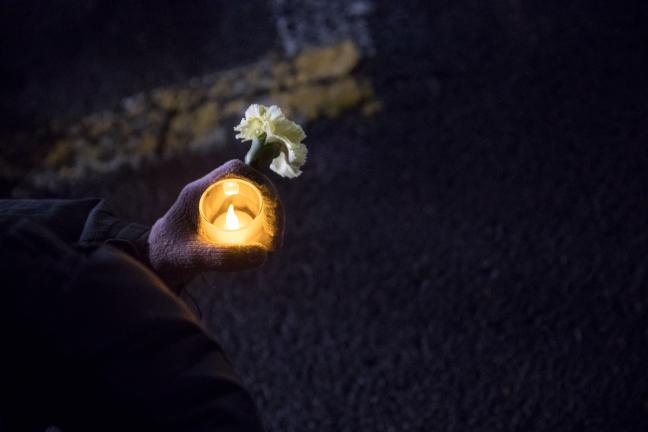 A woman carries a candle in the dark.