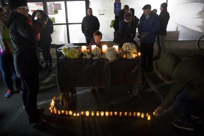 A child watches as adults remember those lost with flowers and light.