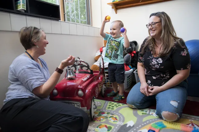 Milo, center, plays with his mother Hilary Milovich, right, and their home visiting nurse Jen Gould.