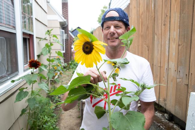 Rich Cowden shows off one of his sunflowers at the "Quest Nest."