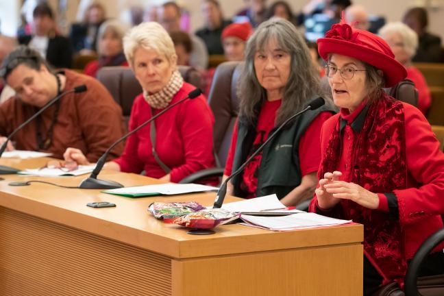 Residents wear red n opposition of fossil fuel development, ask County to take action.