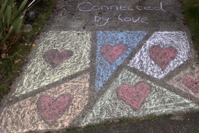 Sidewalk chalk of hearts with the title, "Connected by Love".