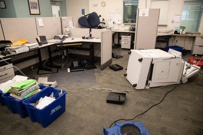 An office with furniture flipped over and strewn about