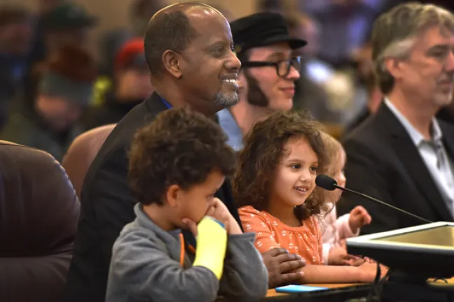 Kayse Jama urged commissioners to pass the e-cigarette ordinance while holding his children. On his left, another father, and vape shop owner Paul Bates, asked the board for exemptions