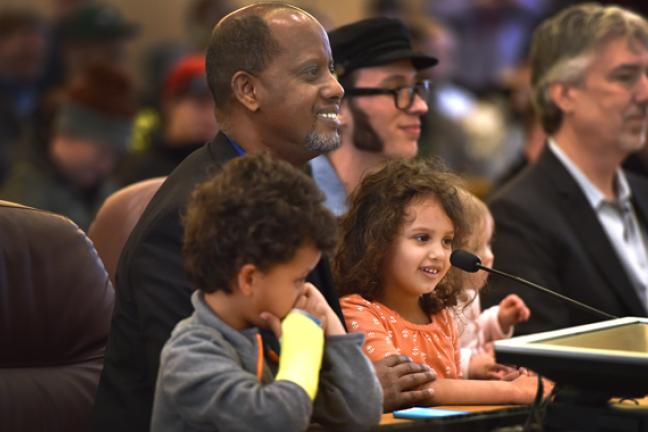 Kayse Jama urged commissioners to pass the e-cigarette ordinance while holding his children. On his left, another father, and vape shop owner Paul Bates, asked the board for exemptions  