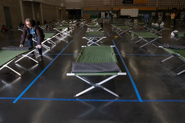 photo of someone setting up cots at the Oregon Convention Center social distancing shelter. 