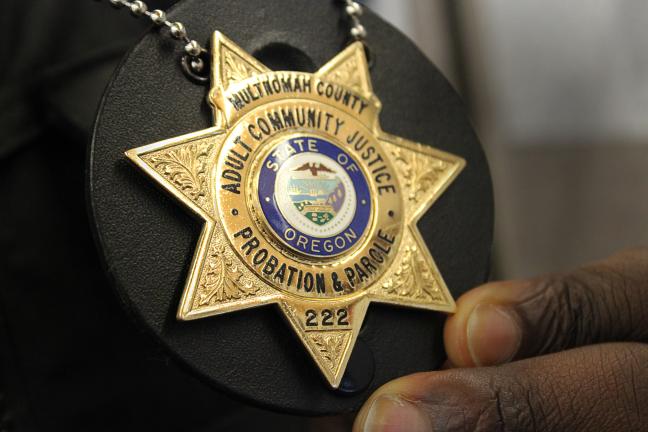 Parole and Probation Officer Jamiel Brown holds his badge