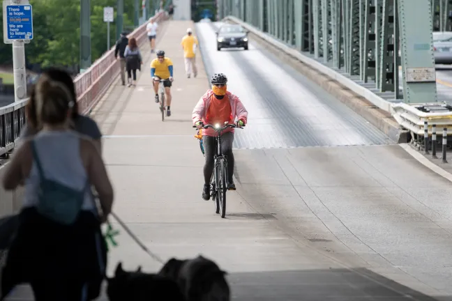 Un ciclista enmascarado cruza el puente Hawthorne del condado de Multnomah durante la pandemia de COVID-19 en 2020.