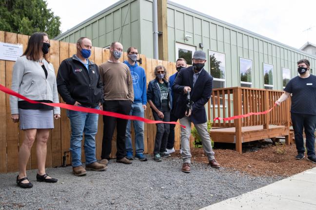 Partners in supporting the St. Johns Village watch Do Good Multnomah director Chris Aiosa cut a ceremonial ribbon on May 21, 2021.