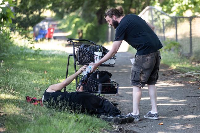 Michael Phelps, outreach worker/case manager, hands out water along with other care items under the record-breaking heat in SE Portland. Cascadia Behavioral Healthcare's Street Outreach Team also offers mental health and housing education.