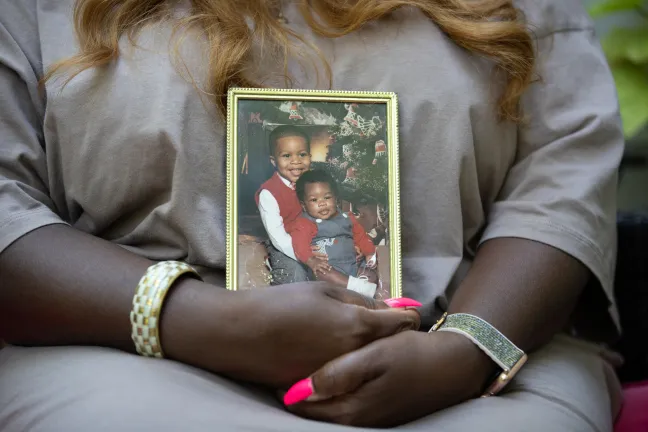 Saunders holds photo of two young sons. Today, they have flourishing careers and families of their own. 